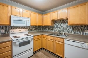 Kitchen showing stove, microwave, sink, and wooden cabinets.